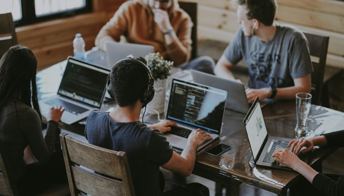 Team meeting around a wooden table with laptops