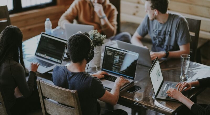 Team meeting around a wooden table with laptops